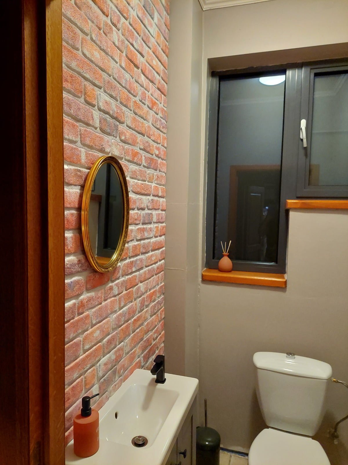 WC avec parement mural brique rouge clair et miroir ovale doré - rénovation toilettes style ancien