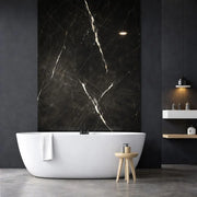 Panneau mural effet marbre noir veiné blanc installé dans une salle de bain moderne avec baignoire îlot
