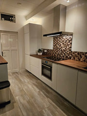 Carrelage adhésif mural hexagone champagne cuivré posé derrière la plaque de cuisson dans une cuisine moderne