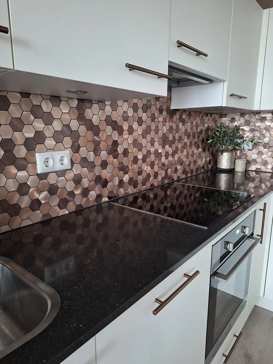 Crédence adhésive hexagone champagne cuivré posée dans une cuisine moderne avec plan de travail noir